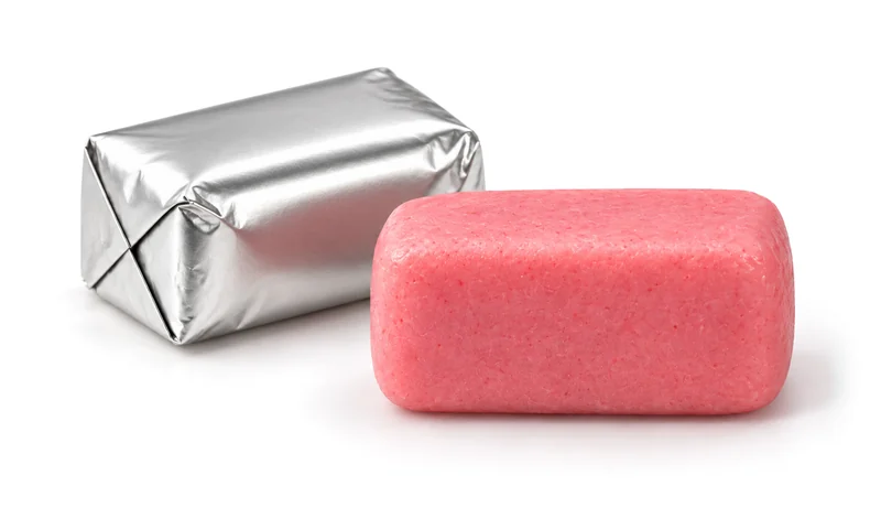One pink soft chew beside one neatly folded silver-wrapped chew